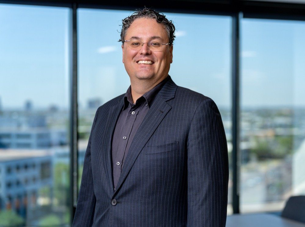Corporate headshot made on location in an office conference room, with floor to ceiling windows and the city behind